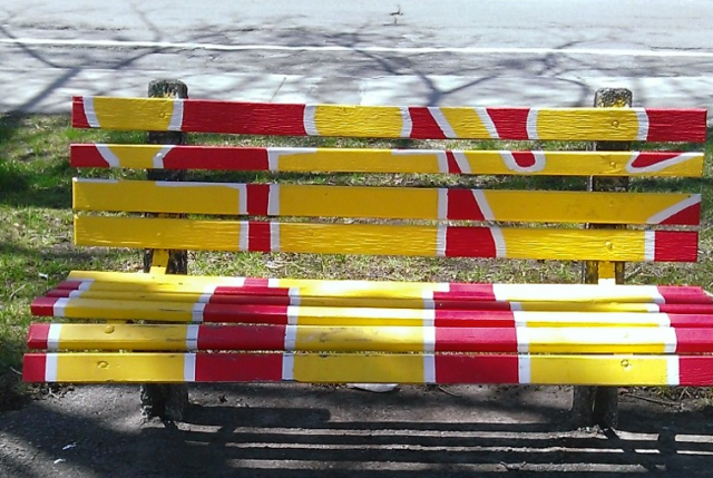park bench painted with outlines of three people sitting